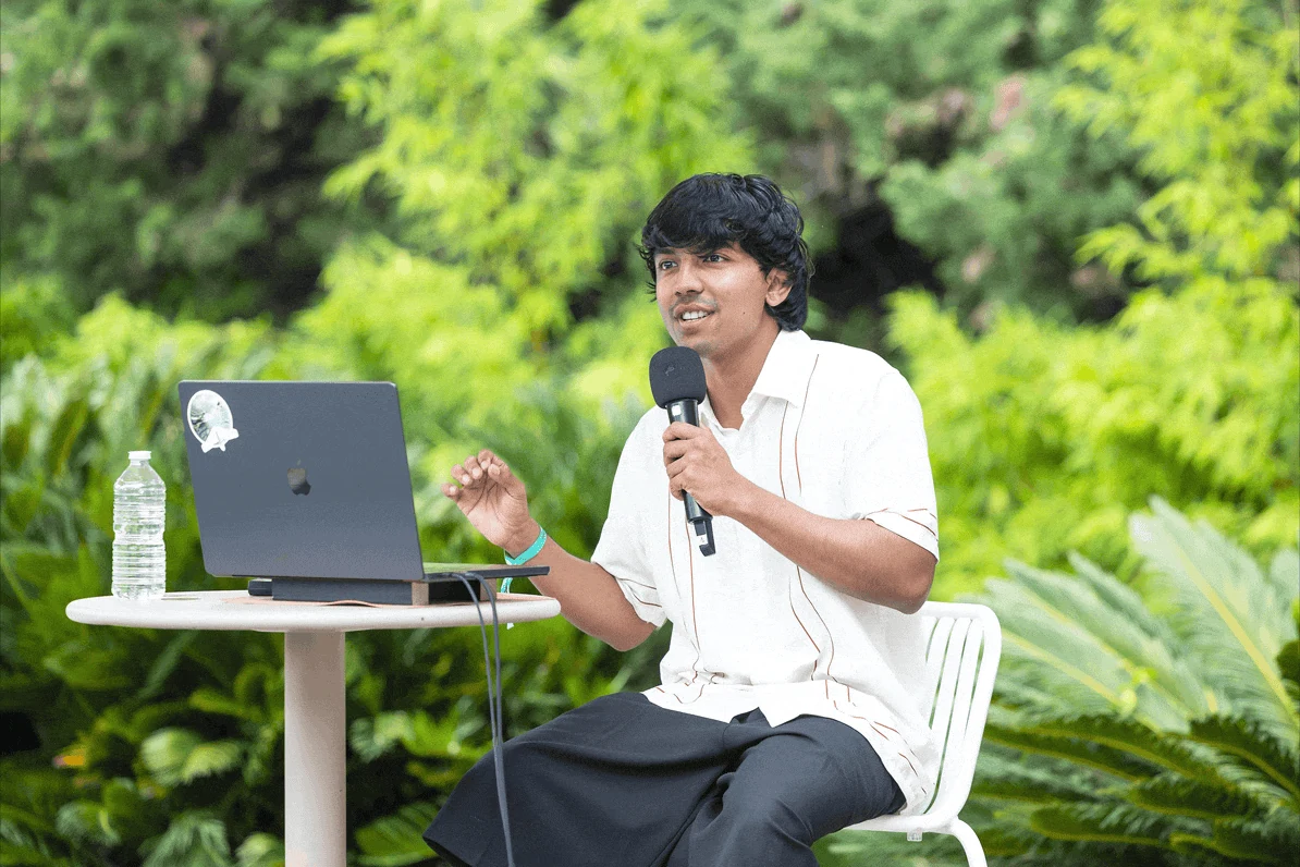 Shashwath Santosh seated outdoors and speaking into a microphone.