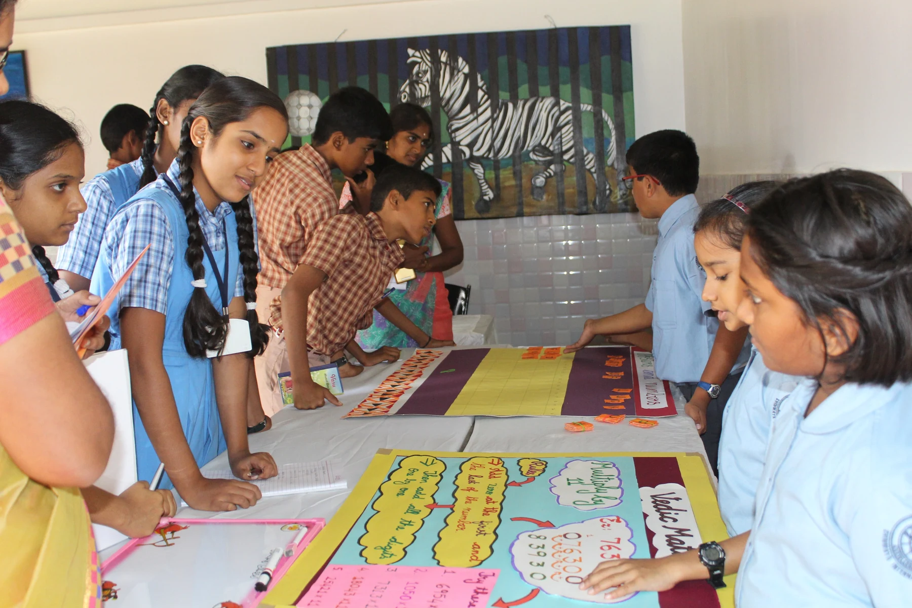 Students reading work laid out on tables at an exhibition