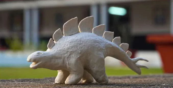 Photograph of a white clay stegosaurus on a ledge