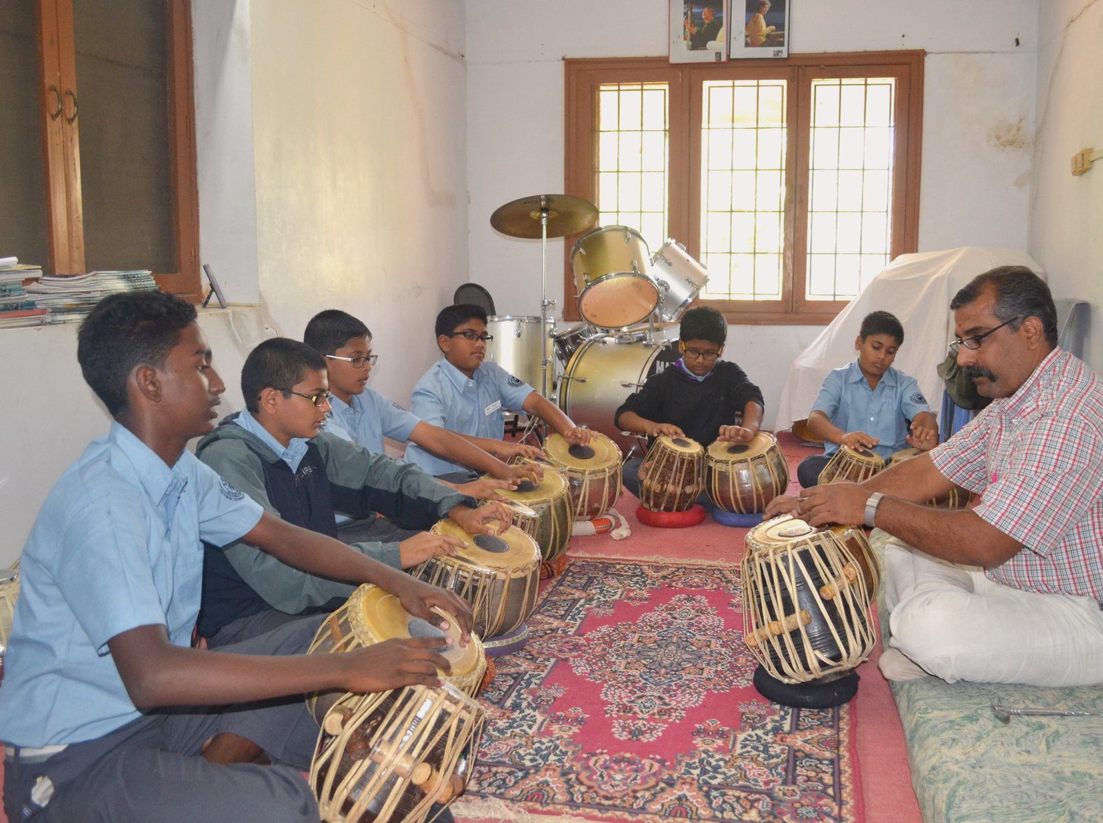 CIRS students seated on a carpet at tabla, their teacher beside them