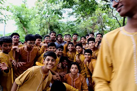 Boys in saffron kurtas gathered together, smiling at the camera
