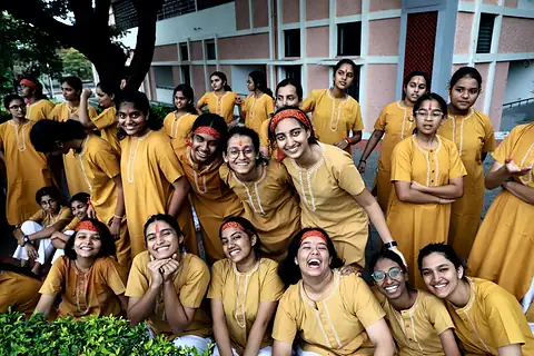 A group of girls in saffron laughing together by the water