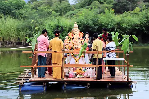 The Ganesh murti on a raft decorated with banana stems, teachers standing around it