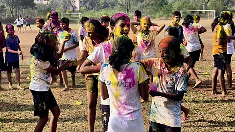 Students with colour on their faces and clothes crossing the playing field