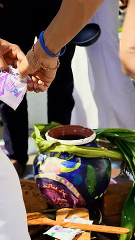 A painted clay pot tied with turmeric leaves on a wooden board