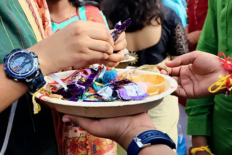 Hands reaching for chocolates from a plate held out by a student