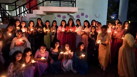 Students holding lit diyas on Diwali evening