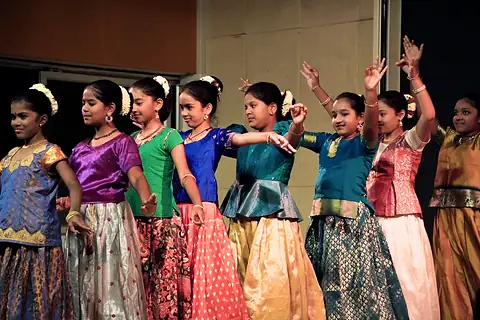Girls in bright traditional skirts dancing in a row on a stage