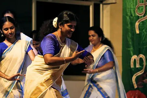 Performers in white and gold saris dancing on a stage