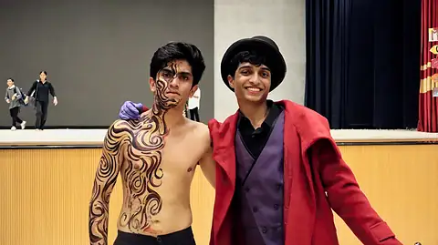 Two actors after the show, one in swirling body paint, one in a red coat and top hat