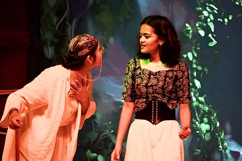 Two performers facing each other in warm light
