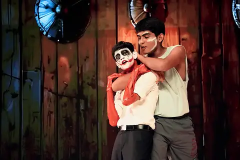 An actor holding another, in skull face paint, from behind