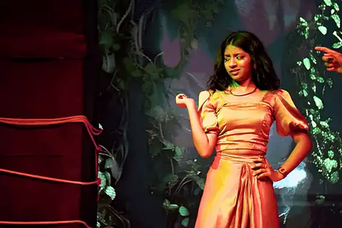 A performer in an orange satin dress, one hand on her hip