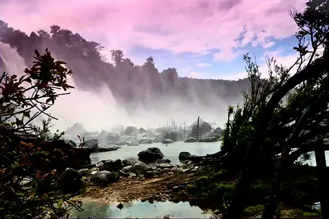 Photograph of a misty waterfall behind rocks and bare trees under a pink evening sky
The Crossroads, Issue 33 · October 2026