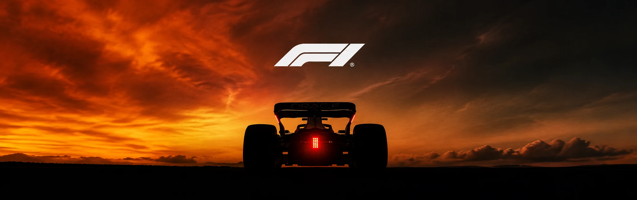 Rear view of a Formula 1 car silhouetted against a fiery sunset sky