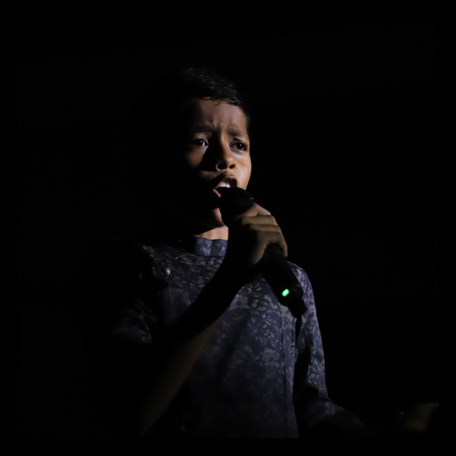 A singer holding a microphone on a dark stage