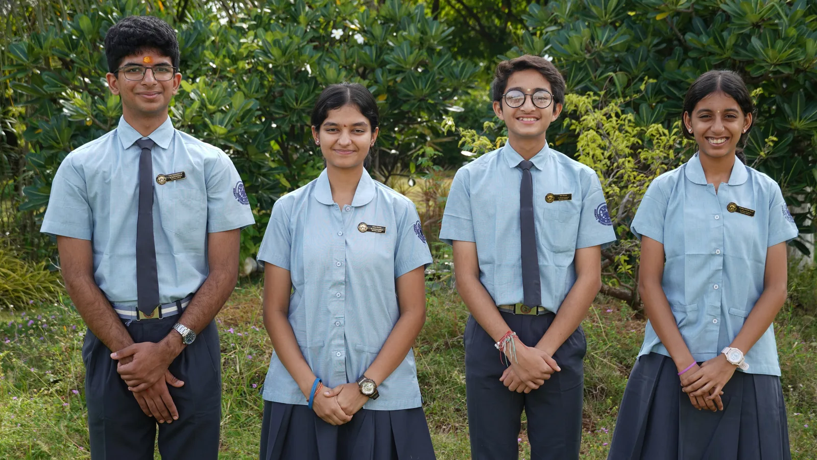 The four Cultural Secretaries of the Student Council 2026–27 standing in a row before green shrubs