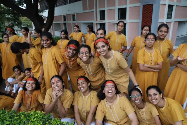 A group of girls in saffron laughing together by the water