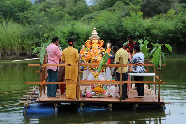 The Ganesh murti on a raft decorated with banana stems, teachers standing around it