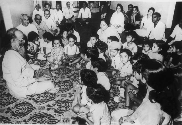 Swami Chinmayananda with a seated gathering including children.