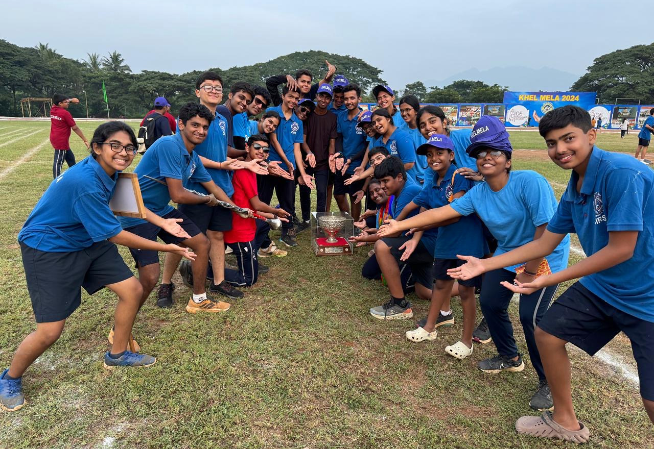 Vyasa students gathered around a trophy on the school field