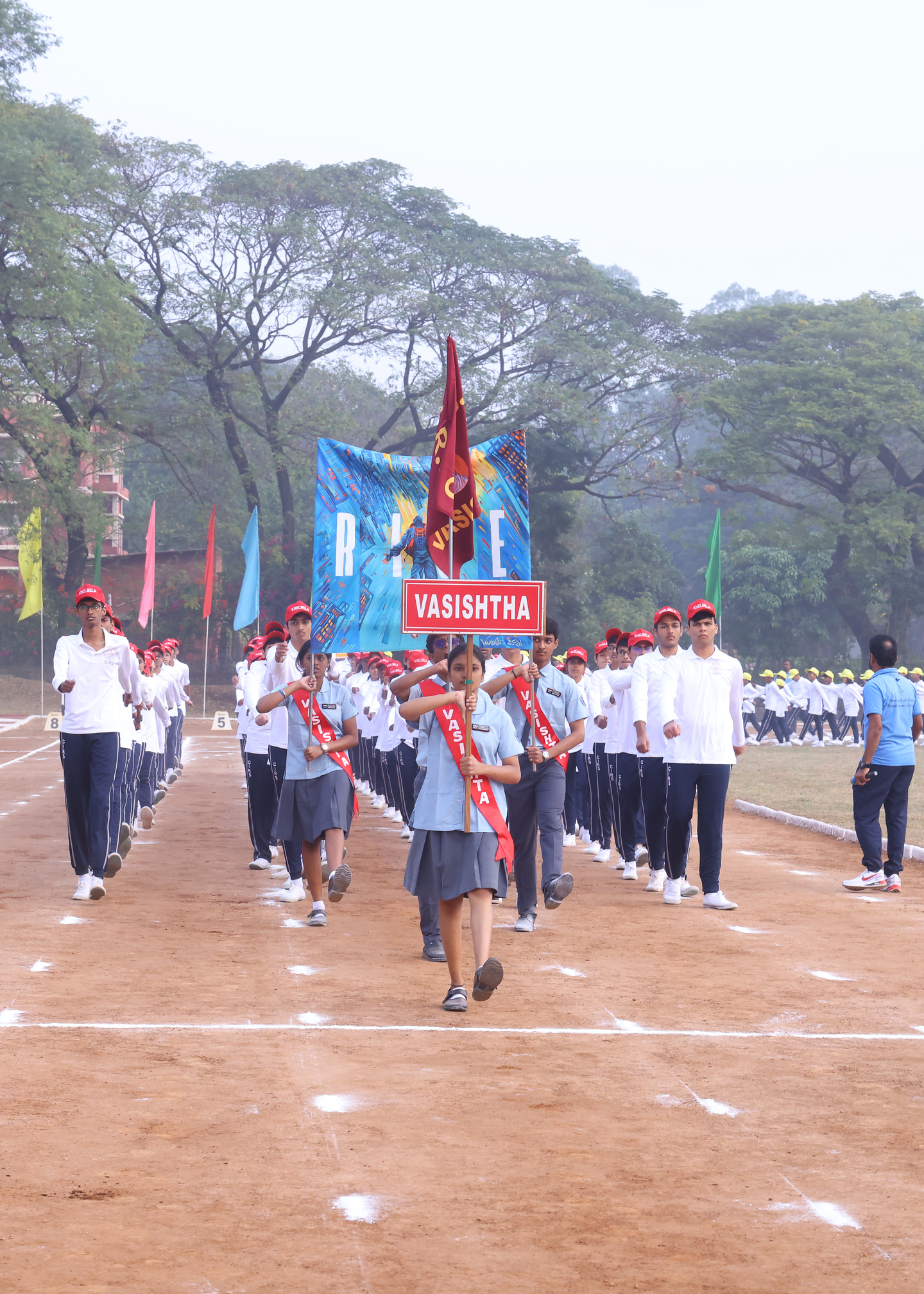 Vasishta students marching behind their named red house banner