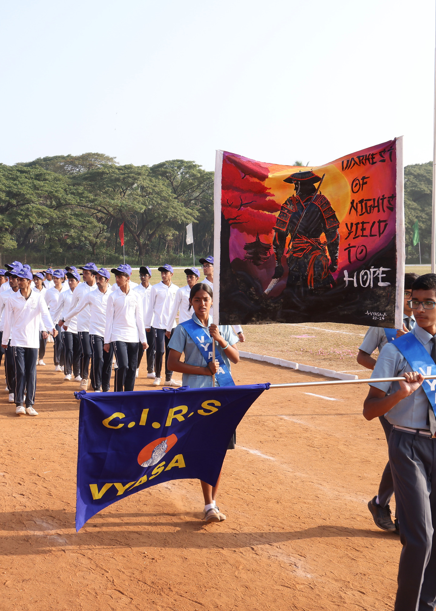 Vyasa students marching behind their named blue house banner