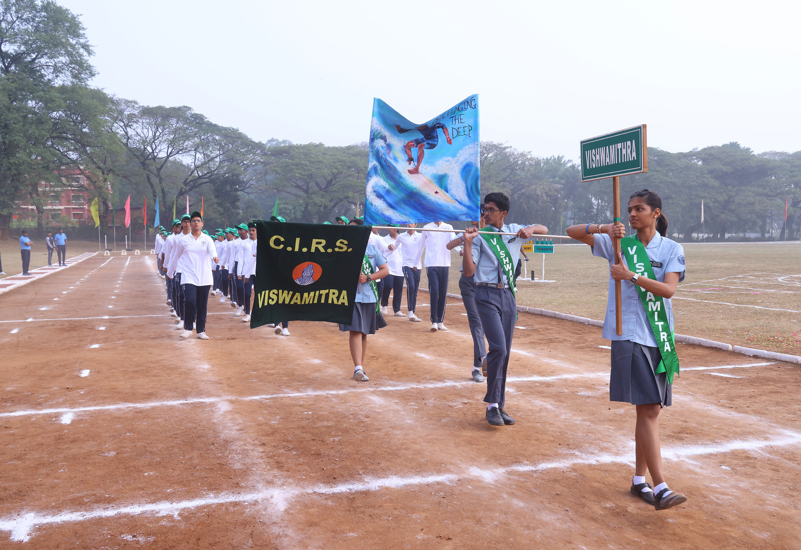Vishwamitra students marching behind their named house banner and flag
