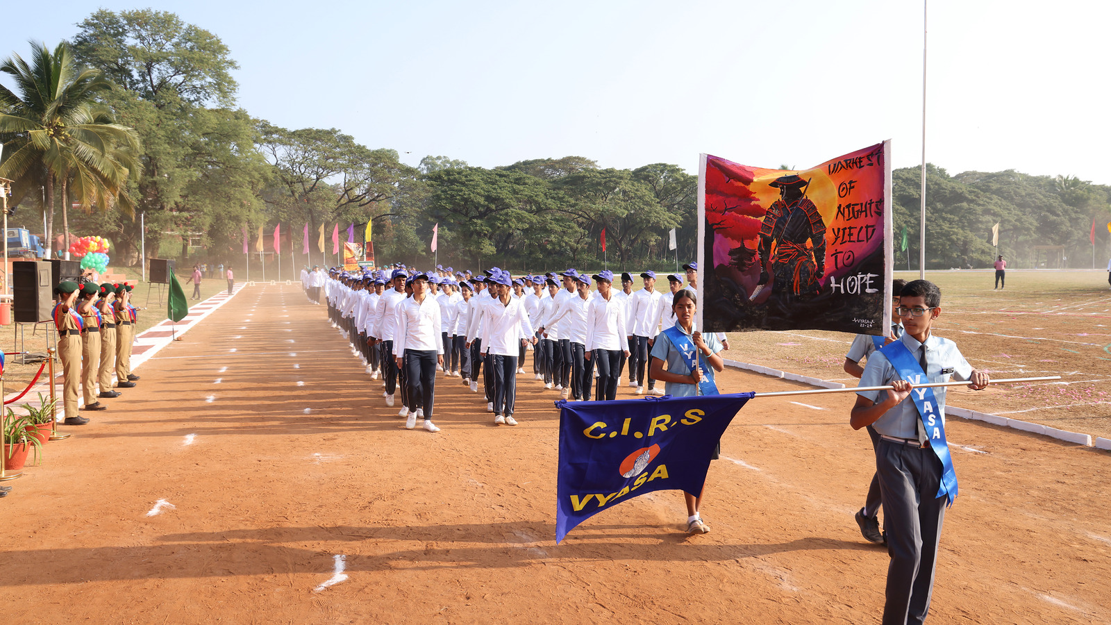 Vyasa students marching behind their named blue house banner