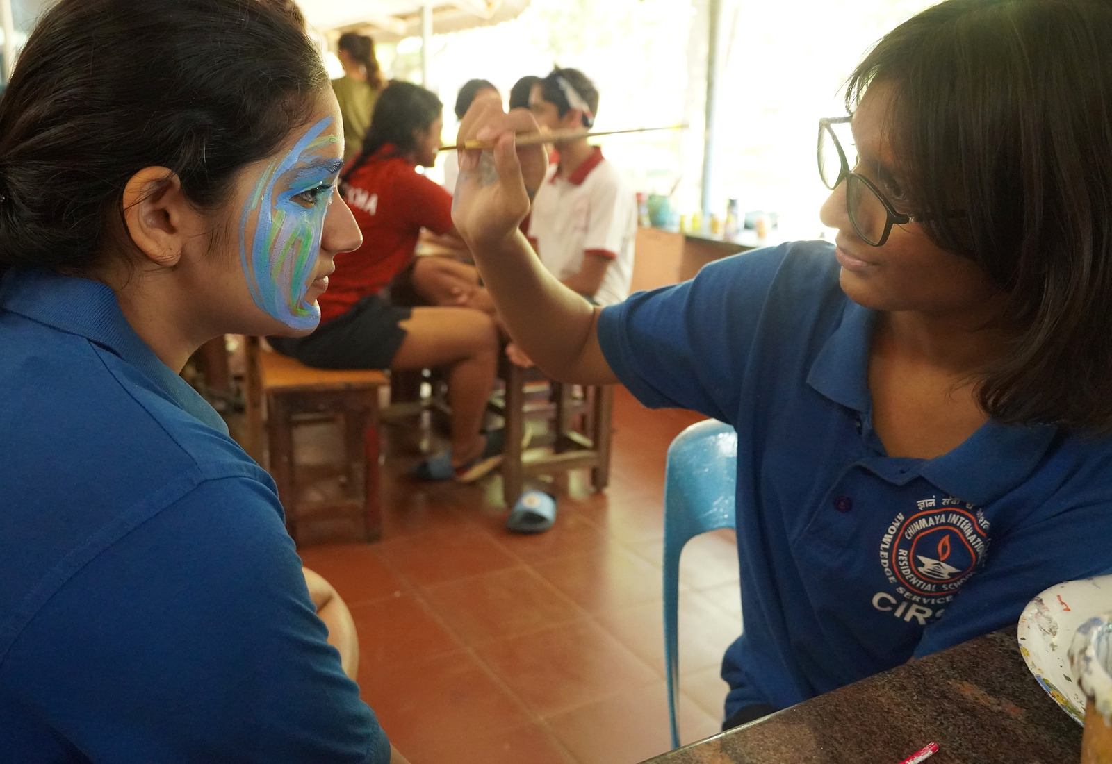 Vyasa students painting a classmate's face during a house activity
