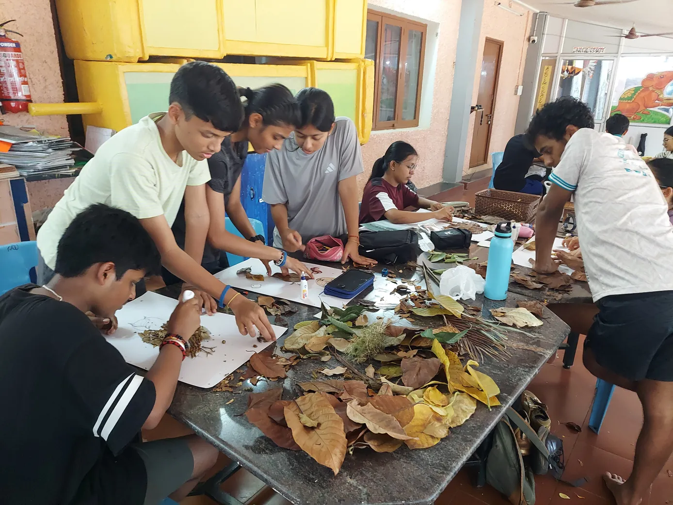 Students arranging dry leaves into compositions in the Art Room