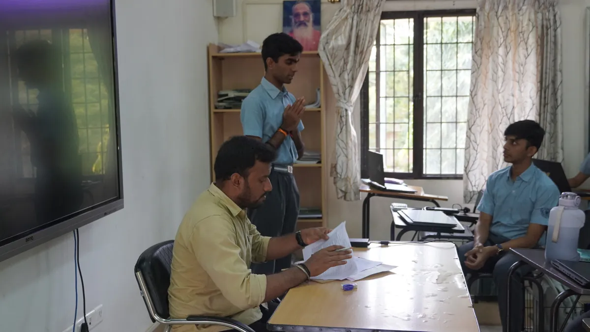A student chanting before a judge at the district-level Gita chanting competition
