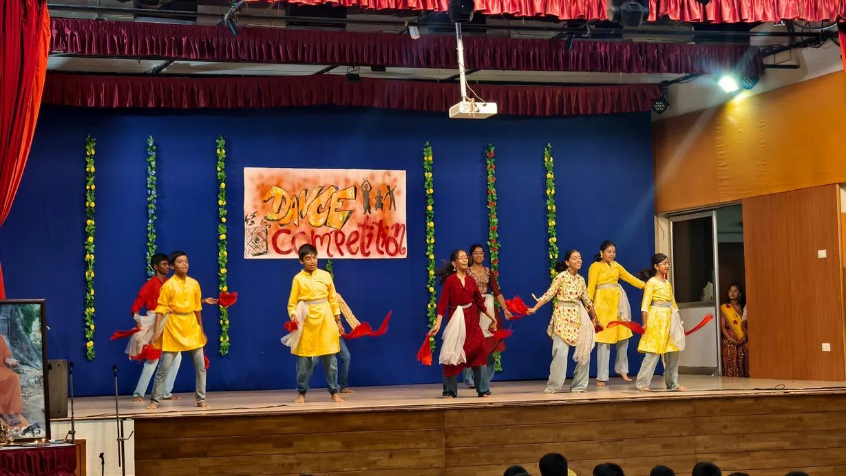 Junior school students in costume performing a group dance on stage in the MPH