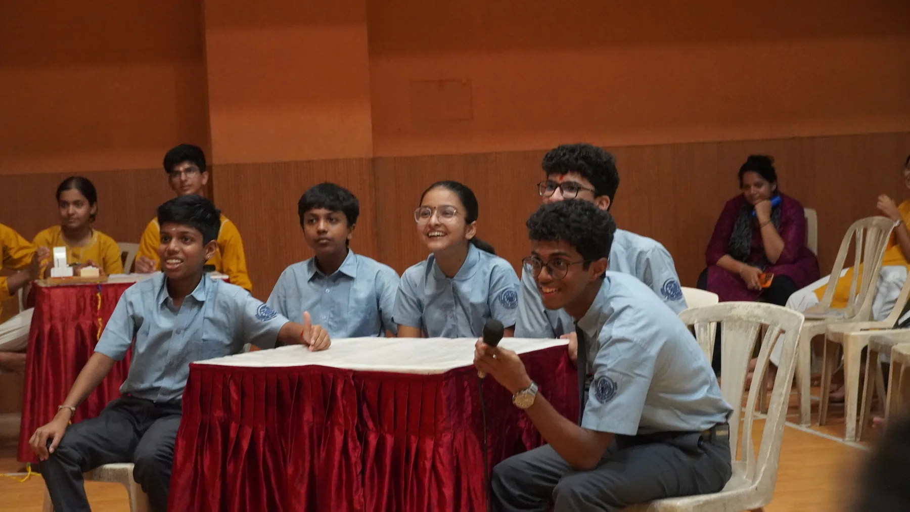 Students seated at a table covered in a red cloth