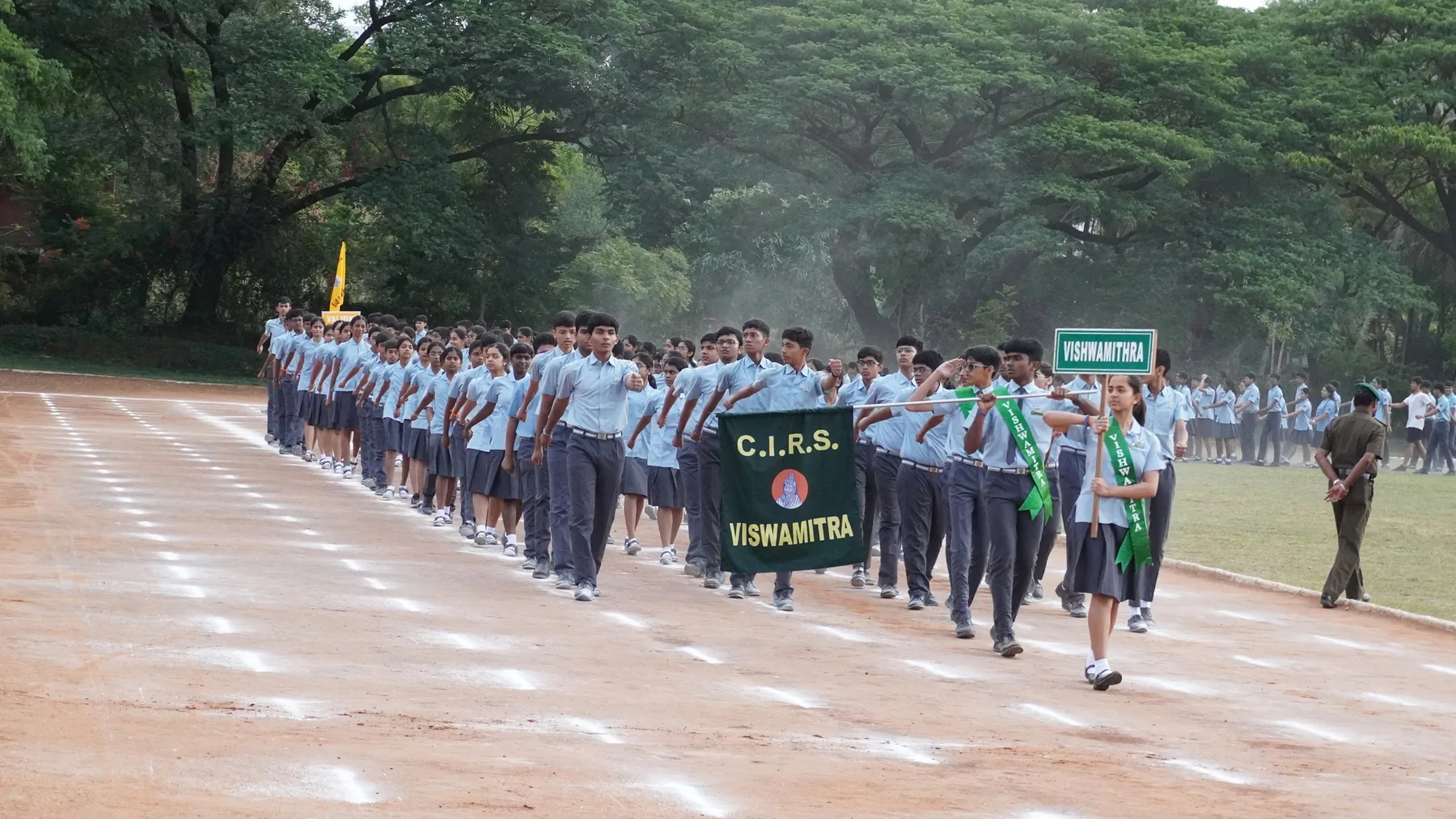 Students marching in formation behind a house banner