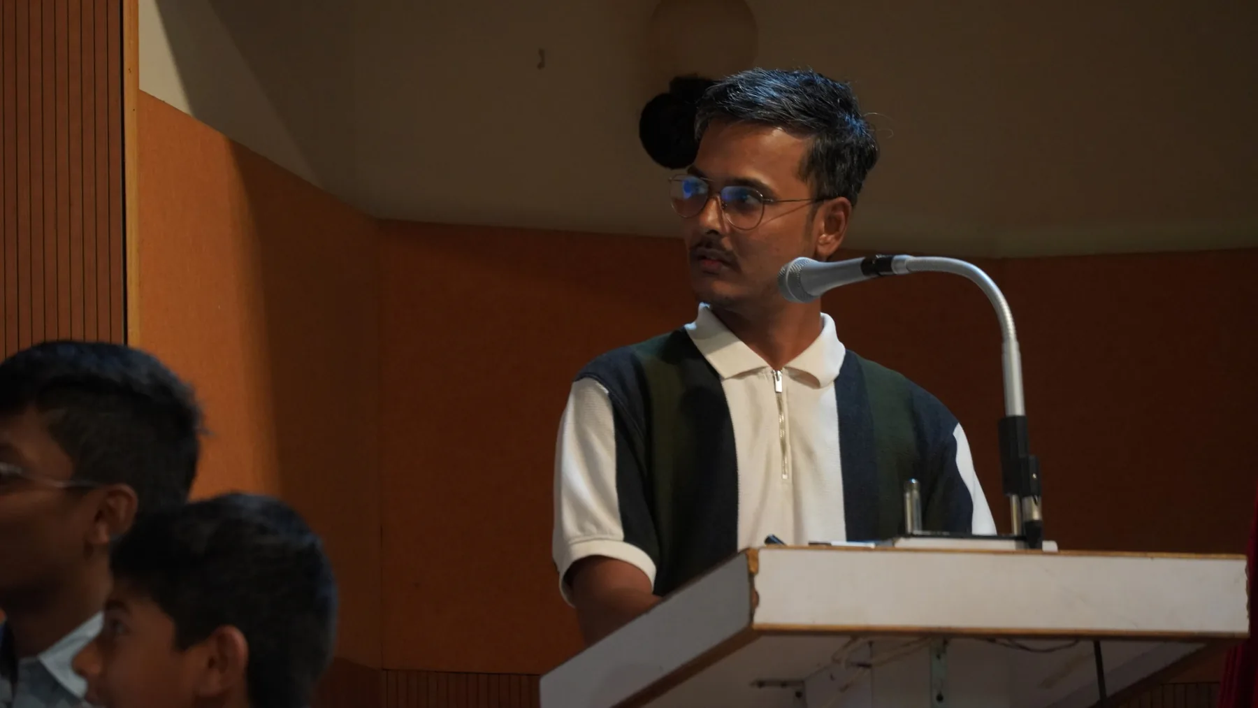 A man speaking at a lectern in a hall