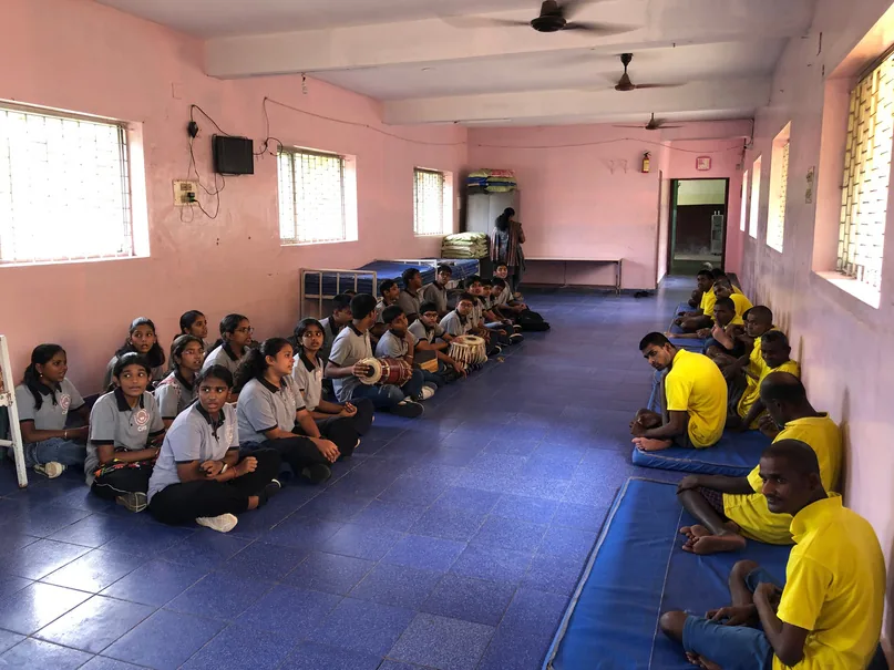 Students seated in rows on blue mats in a hall
