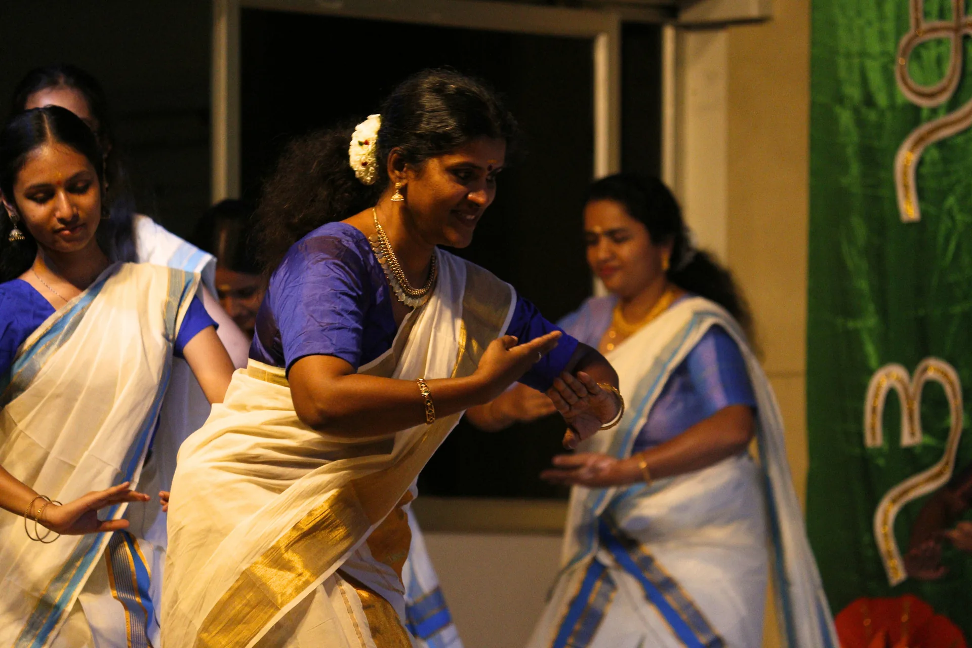 Performers in white and gold saris dancing on a stage