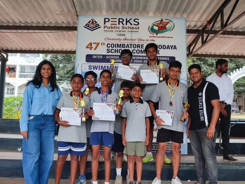 Boys holding medals and certificates beneath a Perks Public School banner