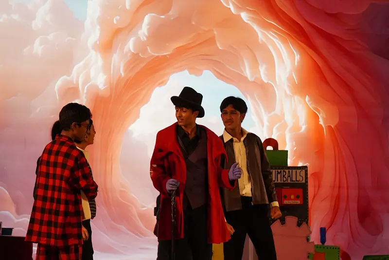 Actors before a swirling pink tunnel projected behind them