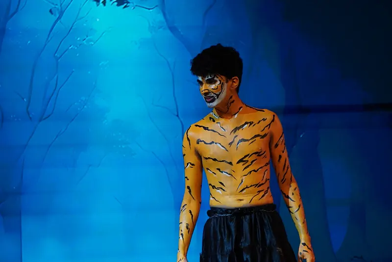 An actor in tiger body paint under blue light