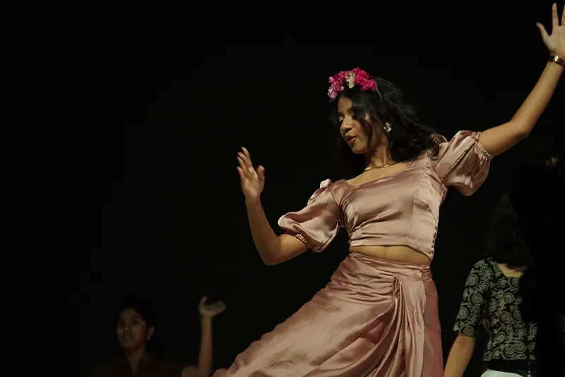 A performer in a satin dress dancing, one arm raised