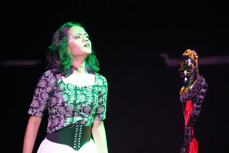 A performer lit green beside a painted skeleton figure