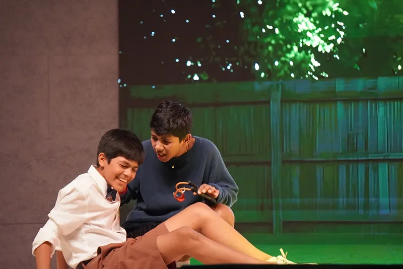 Two boys talking on a lawn before a wooden fence