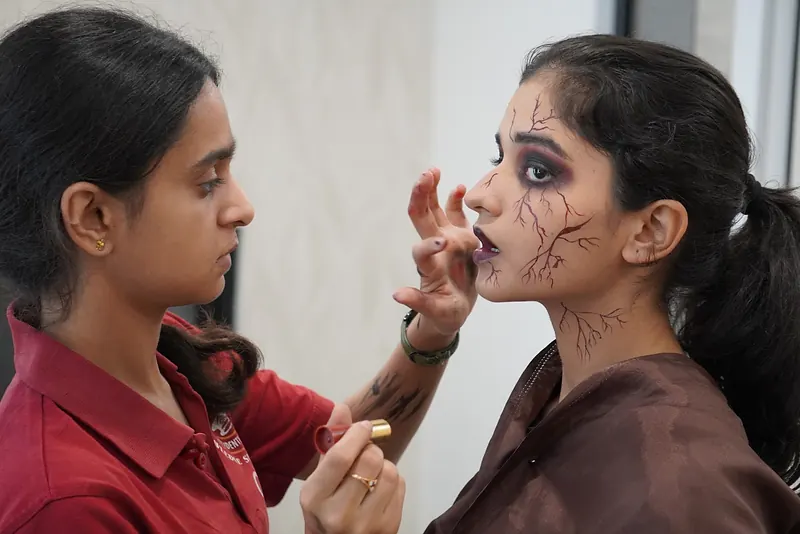 Backstage: a student painting cracks onto a cast member's face